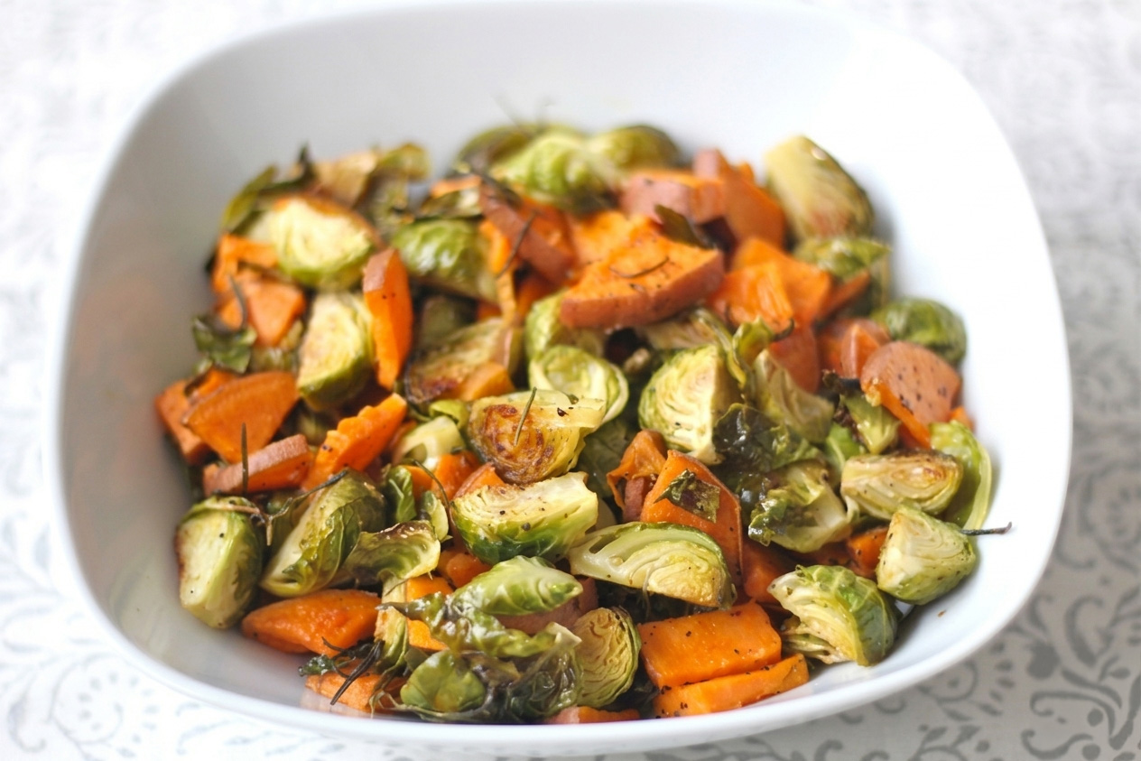 Roasted sweet potatoes and brussels sprouts in a white bowl